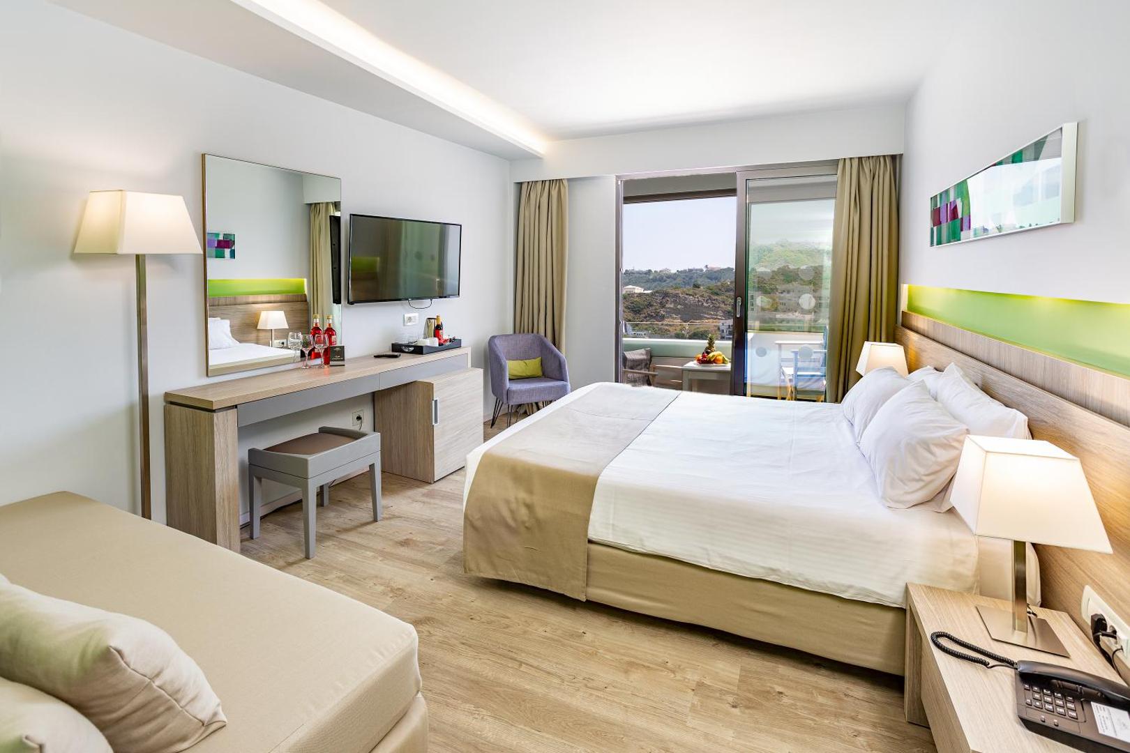Akti Imperial Deluxe Resort moderns divvietīgs numurs ar gaišu koka apdari, lielu gultu un balkonu ar skatu uz kalniem