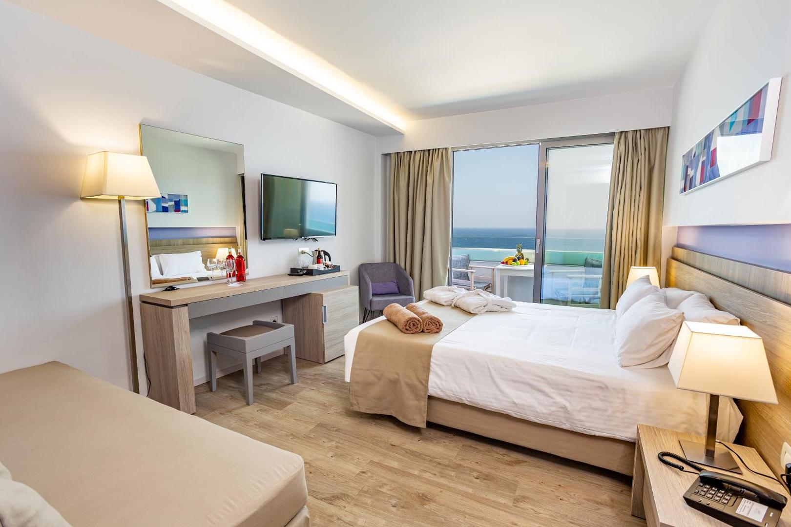 Akti Imperial Deluxe Resort numurs ar skatu uz jūru, sagatavotiem halātiem uz gultas un balkonu Rodas piekrastē