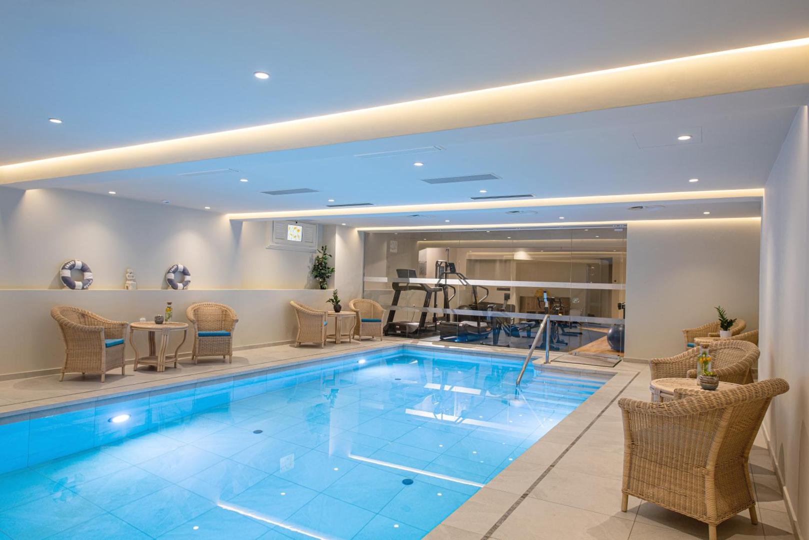 Aelius Hotel and Spa iekštelpu baseins Gūvēs, Krētā — apsildāms baseins ar atpūtas zonu, pītiem krēsliem un skatu uz sporta zāli