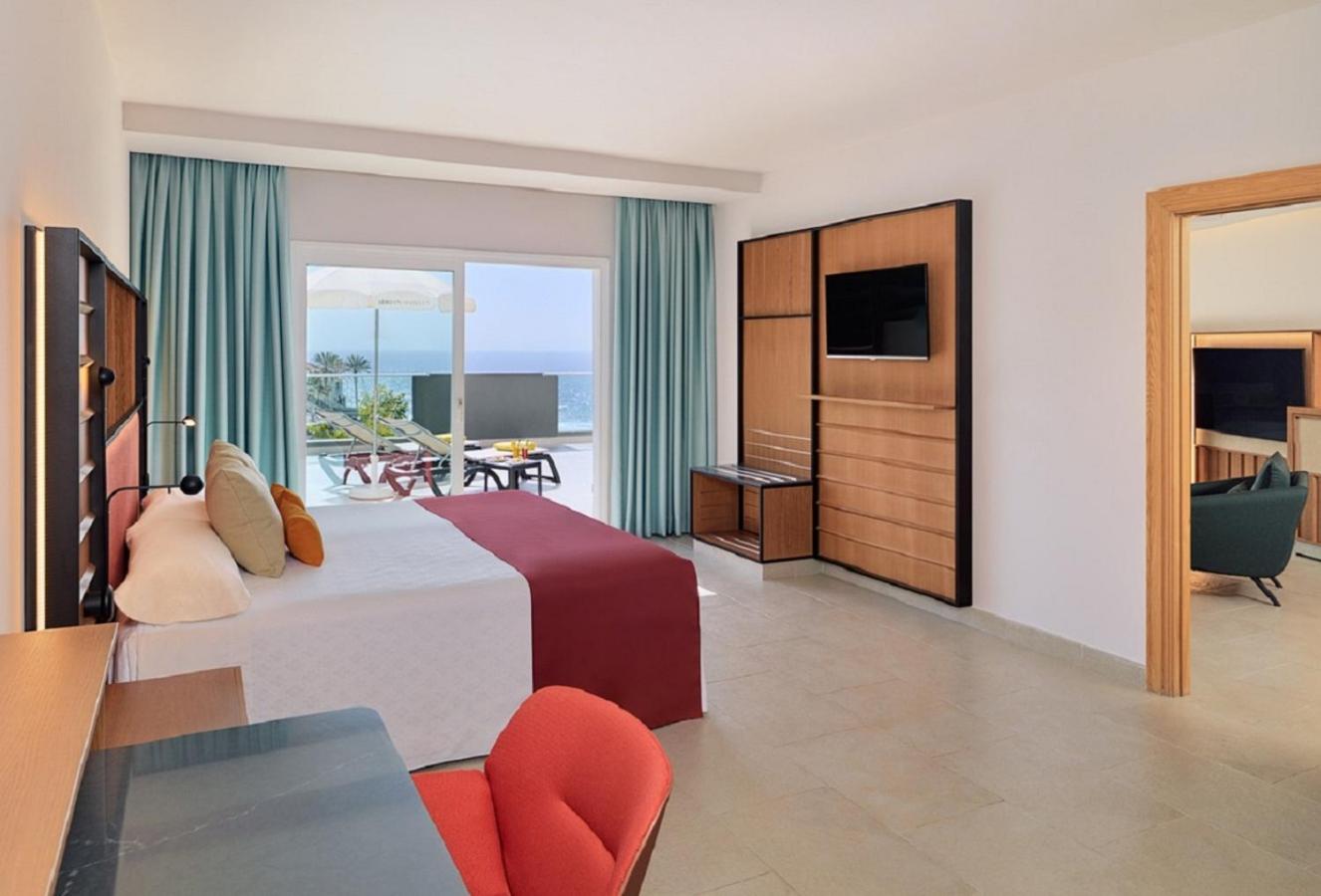 Roca Nivaria Gran Hotel plašs numurs ar skatu uz okeānu, modernām koka mēbelēm, sarkanu krēslu un privātu terasi Tenerifē.