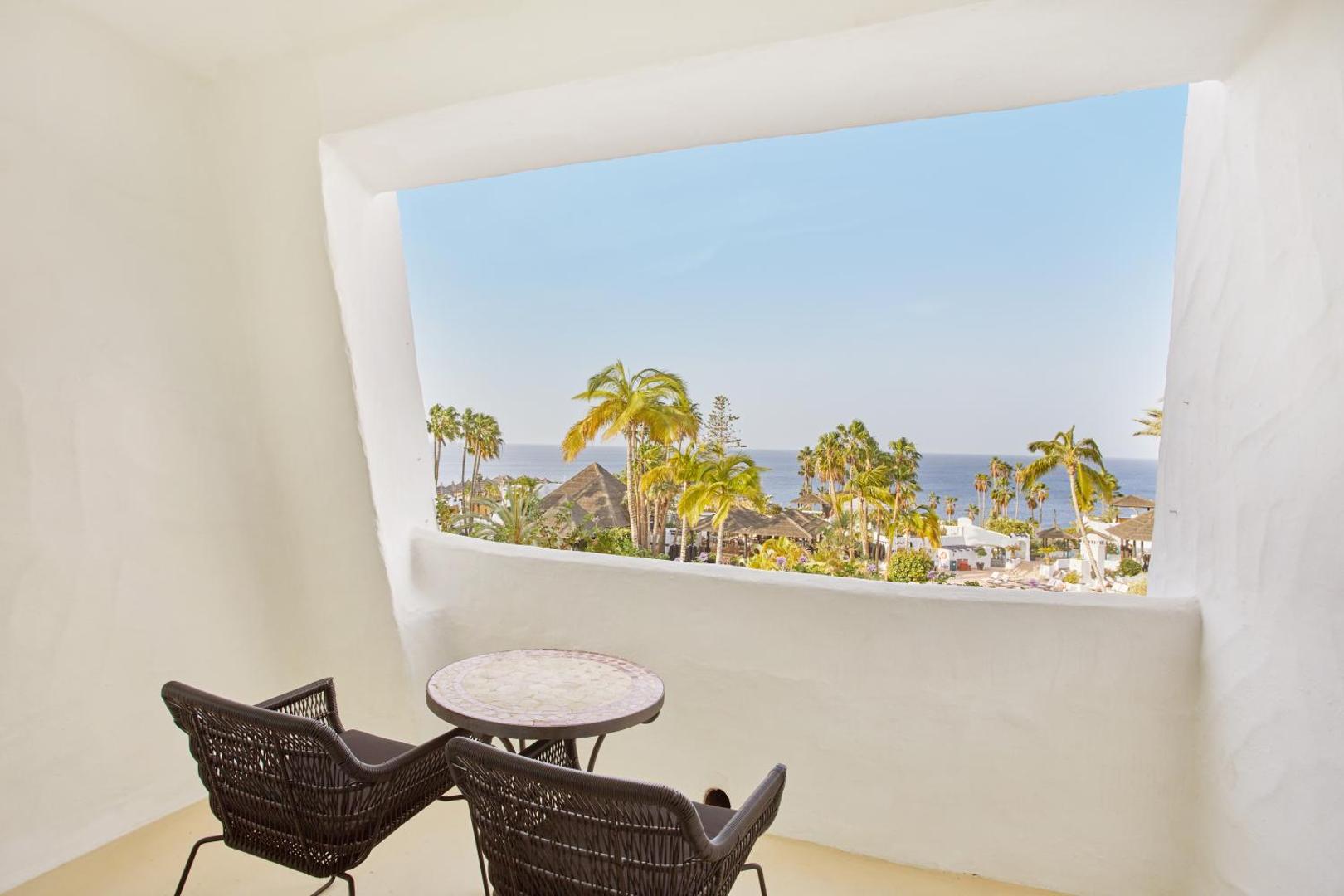 Skats no Dreams Jardin Tropical Resort & Spa balkona uz okeānu, palmām un kūrorta teritoriju Tenerifē