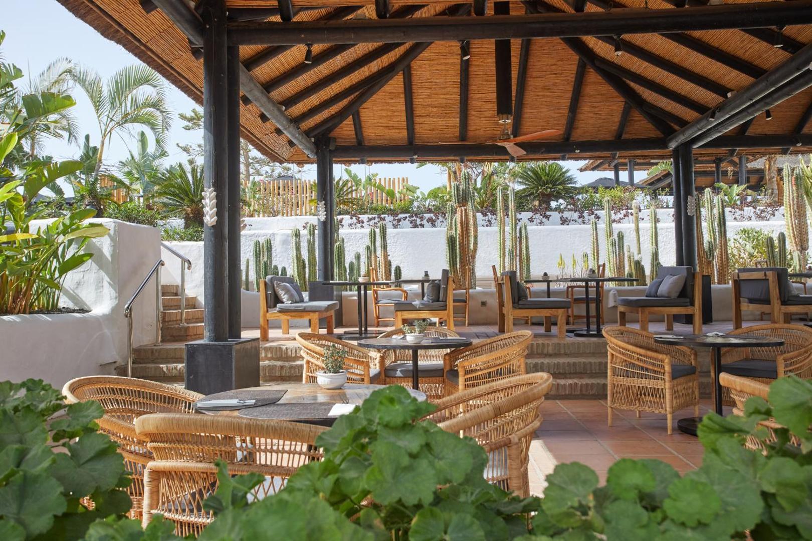 Atvērta tipa terase ar pītiem krēsliem un koka jumtu Dreams Jardin Tropical Resort & Spa viesnīcā, fonā kaktusi un tropu augi