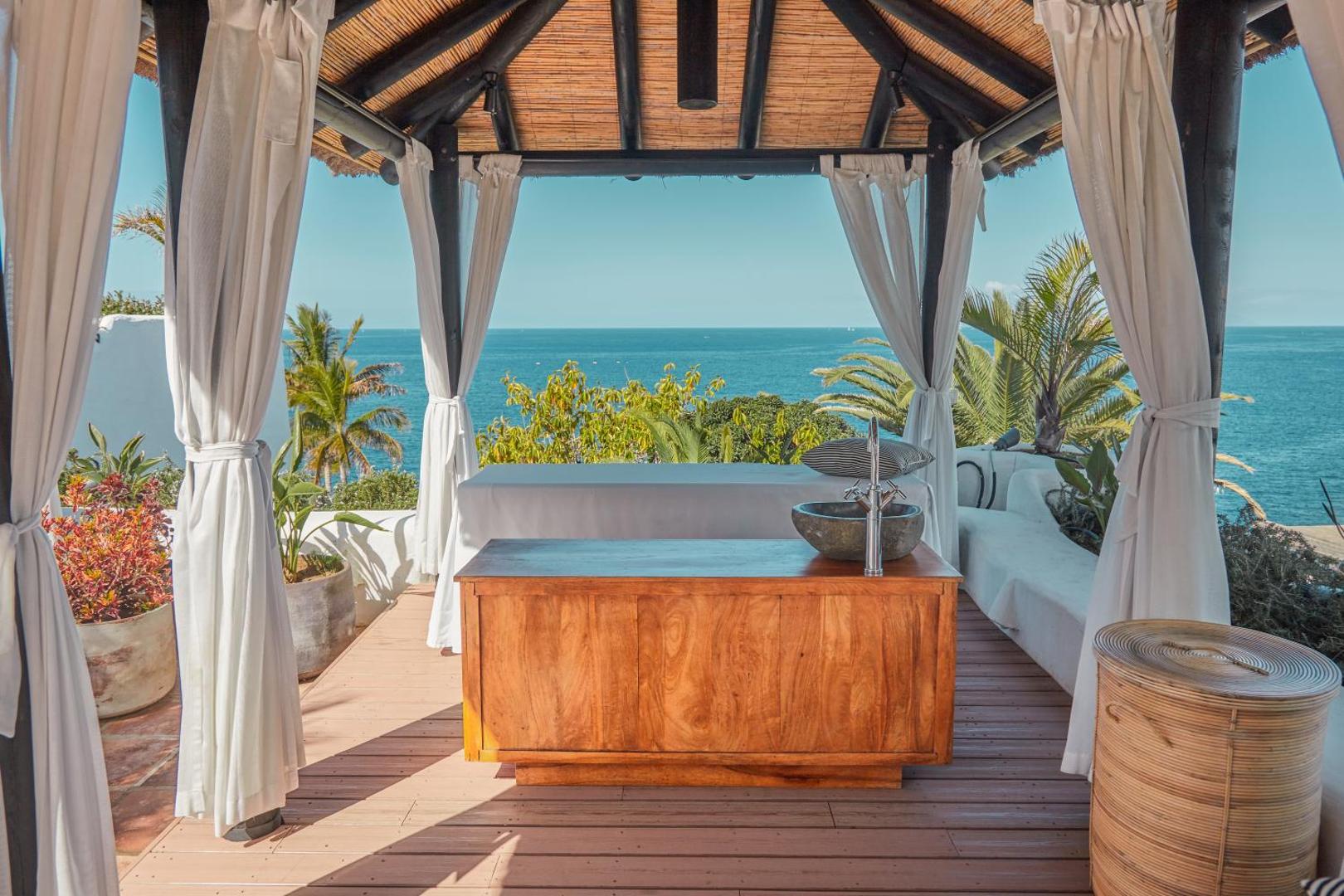 Dreams Jardin Tropical Resort & Spa spa zona brīvā dabā ar skatu uz okeānu un masāžas galdu zem nojumes