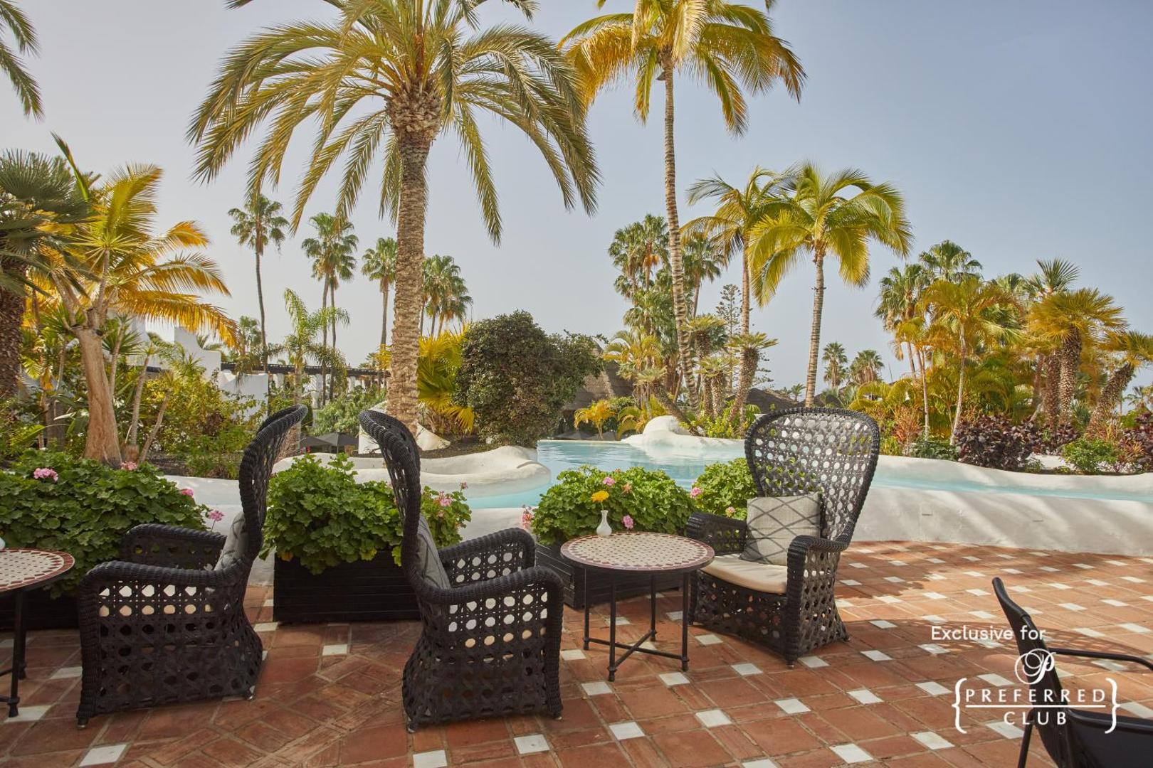Dreams Jardin Tropical Resort & Spa atpūtas zona ar pītiem krēsliem pie baseina un palmām Tenerifē