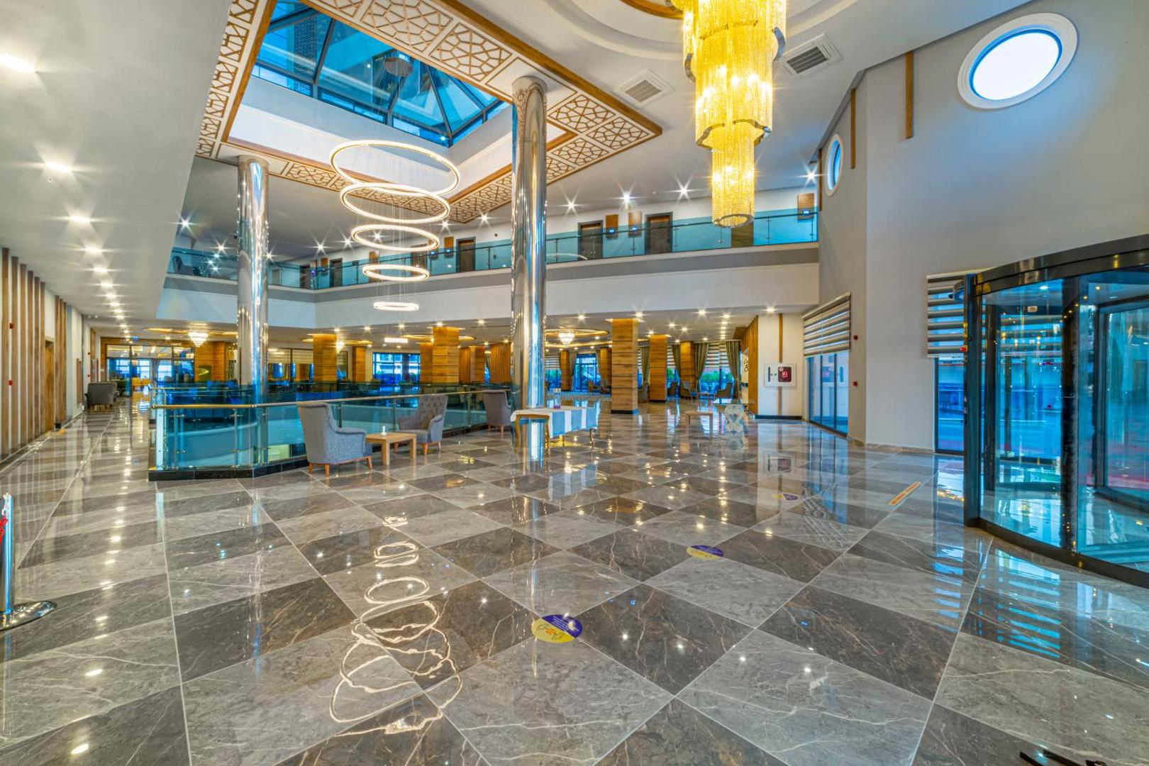 Lonicera Premium viesnīcas lobby halle ar augstiem griestiem, greznām lustrām, marmora grīdu un stikla jumta konstrukciju