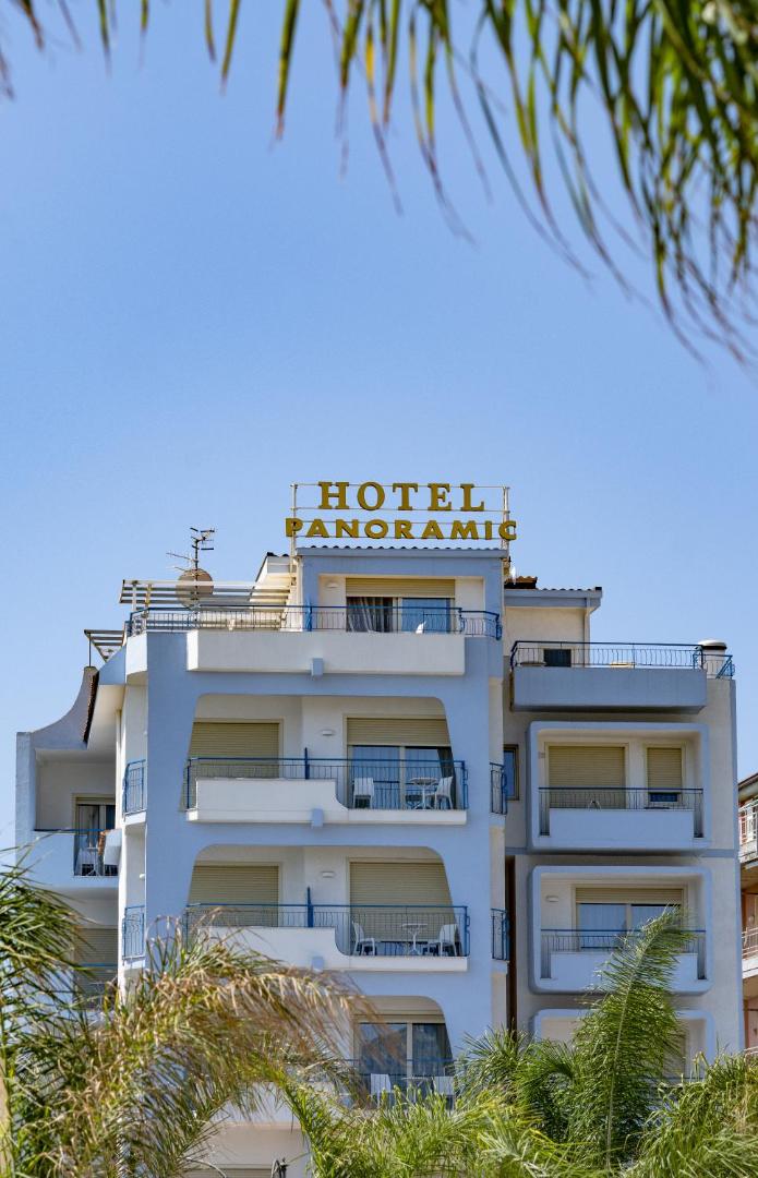 Hotel Panoramic fasāde ar gaiši ziliem balkoniem un viesnīcas nosaukumu uz jumta Giardini Naxos kūrortā Sicīlijā