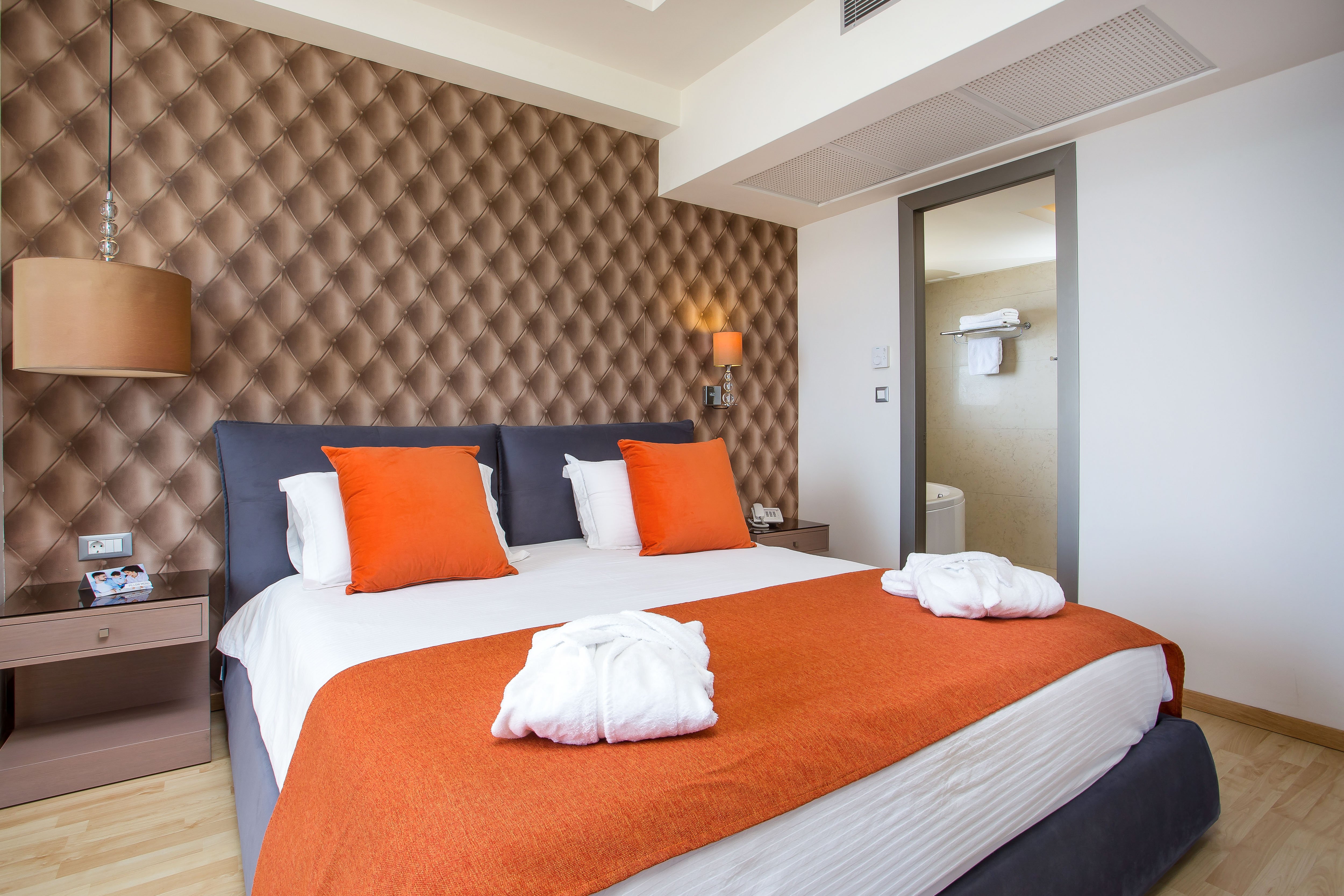 Mūsdienīgs numurs Pegasos Beach Hotel & Resort ar oranžiem akcentiem.