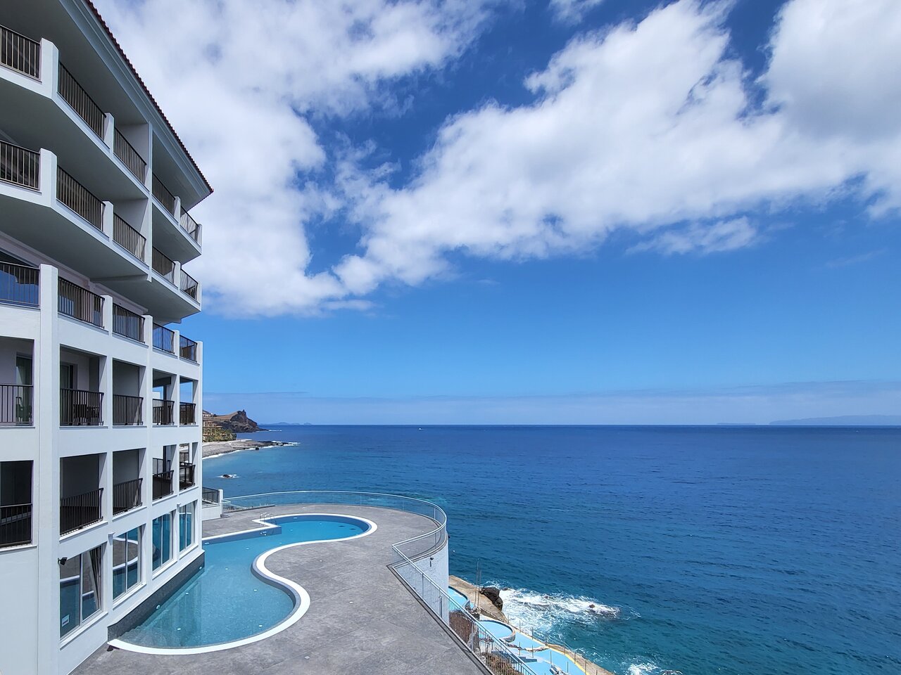Mūsdienīgs piejūras viesnīcas komplekss ar baseinu un skatu uz zilo okeānu un debesīm. Ideāla vieta atpūtai saulainā klimatā. panoramic view with beach and pools
