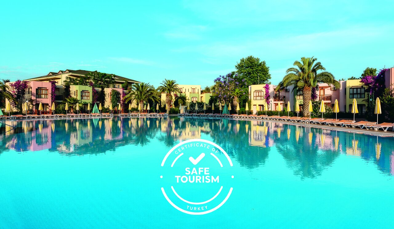 Lielisks kūrorts ar drošu tūrismu, kas atspoguļo skaidro ūdeni un krāsainos ēkas, apzaļumotas ar palmu kokiem un ziediem.