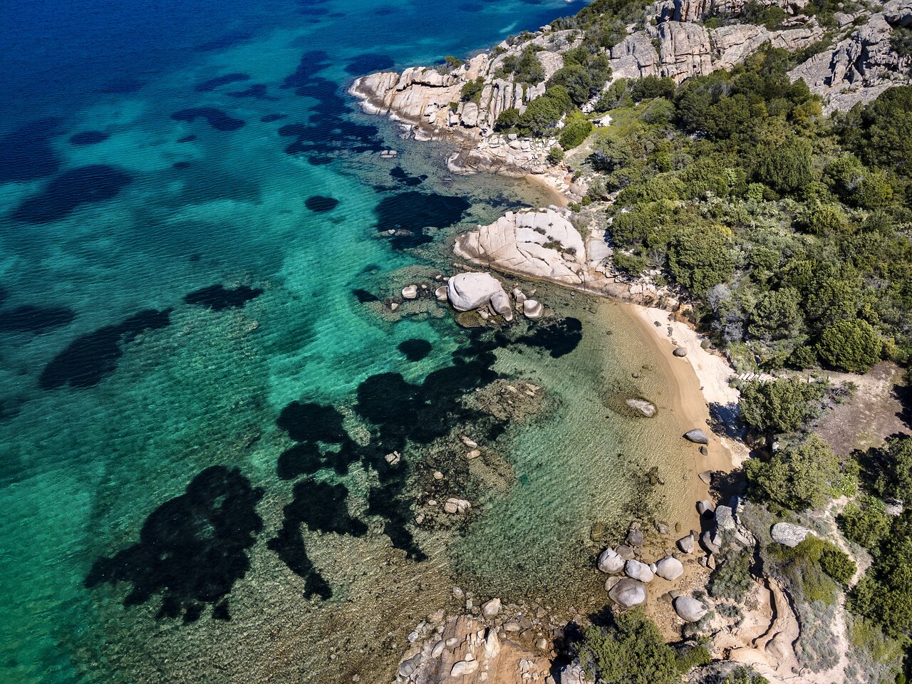 7 Pines Resort Sardinia piekrastes ainava ar kristāldzidru ūdeni.