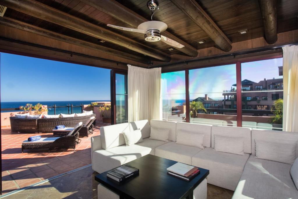 Mūsdienīgs viesistabas interjers ar plašiem logiem, kas piedāvā skatu uz okeānu. Telpā ir ērta dīvāns un galdiņš, radot relaksējošu atmosfēru.