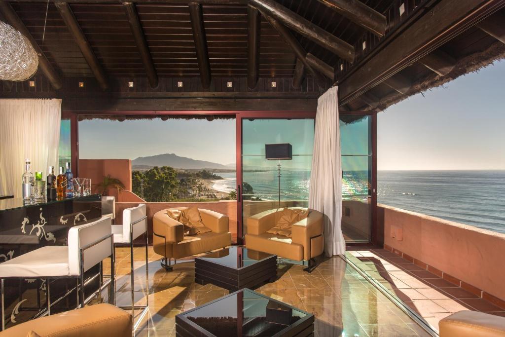 Moderns interjers ar skatu uz jūru, iekārtots ar ērtām sofa un bāra zonu. Lielie logi ļauj ieplūst dabiskai gaismai un sniedz brīnišķīgu skatu uz ainavu.