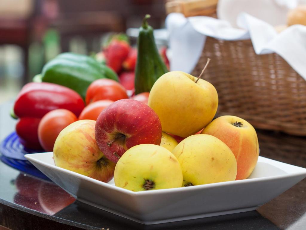 Svaigu ābolu un dārzeņu kompozīcija uz galda, kas ietver zaļos un sarkanos piparus.