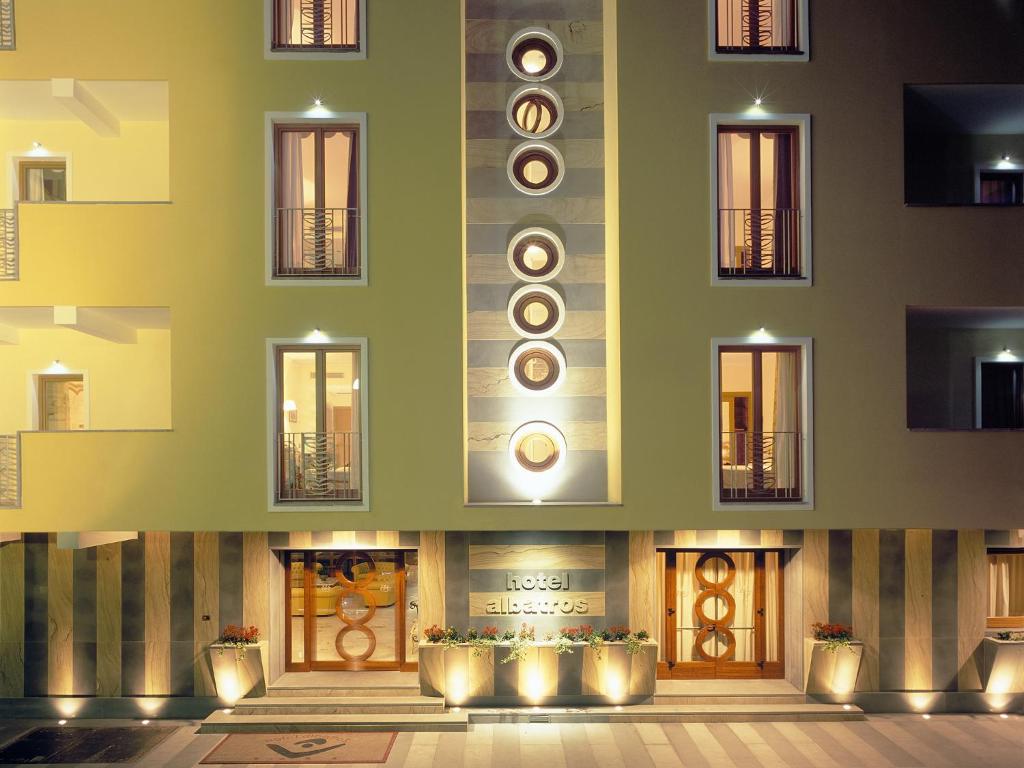 Moderns viesnīcas eksterjers ar unikālu dizainu un apgaismojumu, kas rada siltu un viesmīlīgu atmosfēru. Ievērojami apaļi logi un dekoratīvas augu podi pie ieejas.