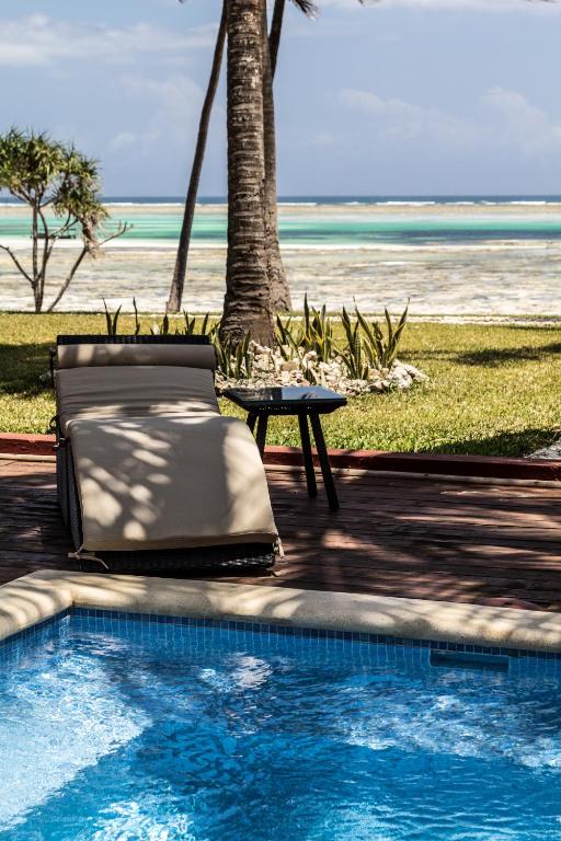 Atpūtas krēsls pie baseina ar skatu uz jūru Karafuu Beach Resort & Spa.