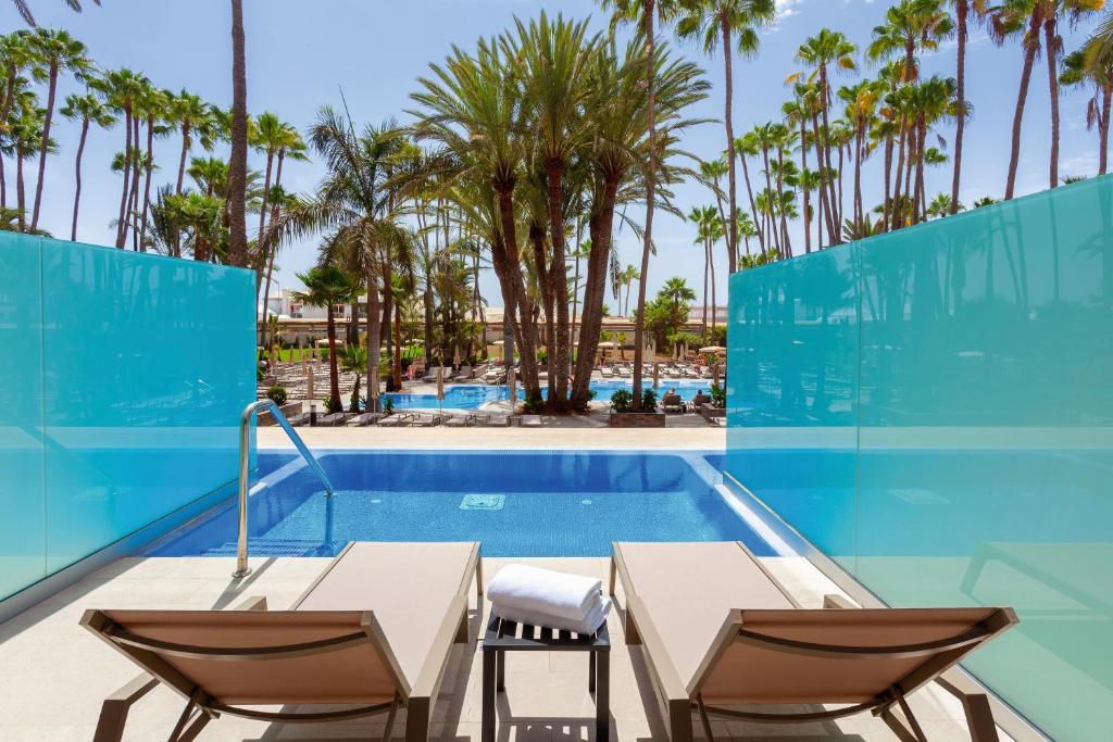 Mūsdienīga atpūtas zona ar baseinu, palmām un saulessargiem, kas piedāvā relaksāciju un komfortu. Ideāla vieta atpūtai siltā klimatā.