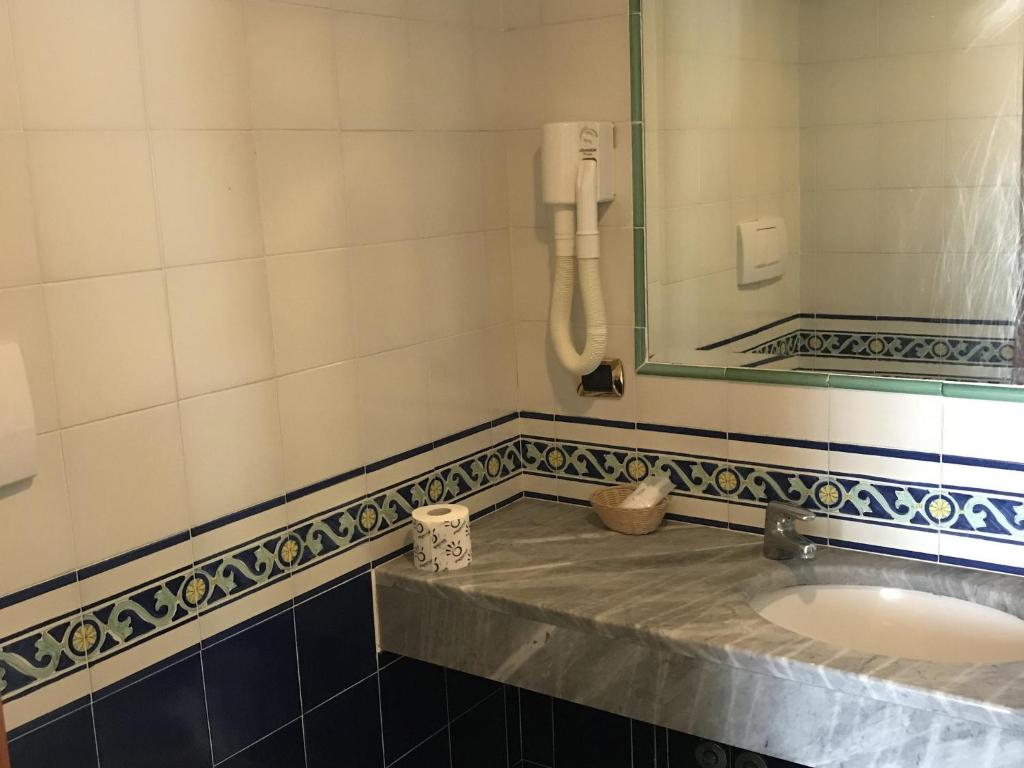 Vannas istaba ar marmora izlietni un flīžu apdari, kurā redzams spogulis un fēns. Eleganta un funkcionāla dizaina elementi piešķir telpai patīkamu atmosfēru.