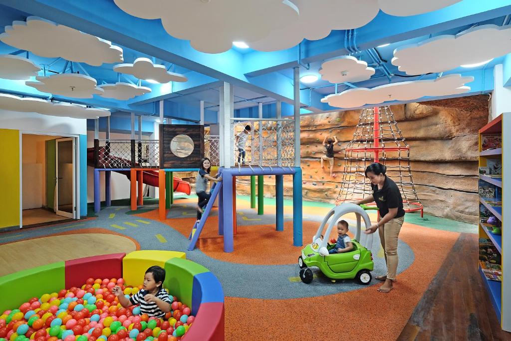 Bērnu rotaļu laukums Jambuluwuk Oceano Seminyak, ar krāsainām bumbiņām, slidkalniņu un kāpšanas sienu.