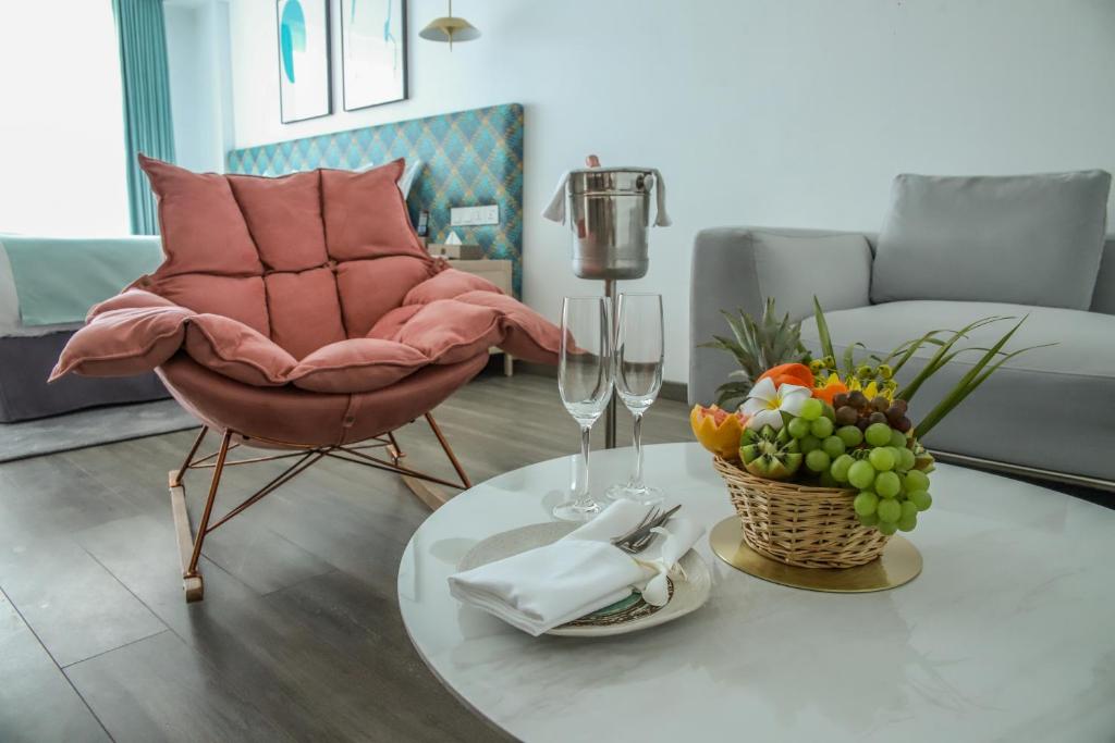 Mūsdienīgs viesnīcas numurs Ocean V ar komfortablu rozā krēslu un augļu grozu.