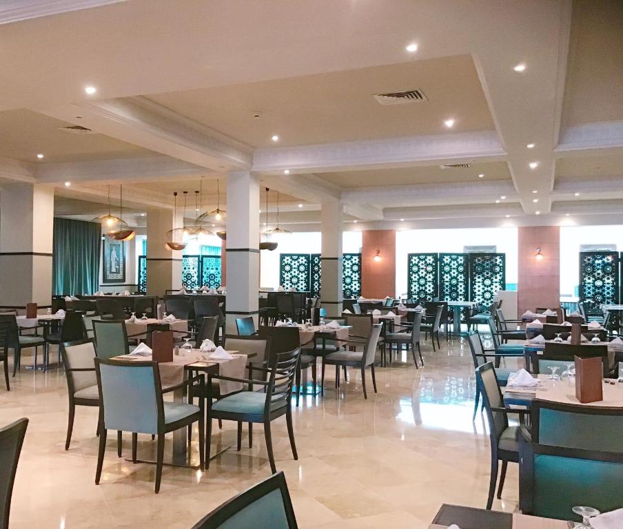 Mūsdienīgs restorāns ar elegantu interjeru, kurā redzamas ēdamgalds un krēsli, apgaismojums un dekoratīvas akcenti. Telpa ir plaša un gaiša, radot komfortablu atmosfēru.