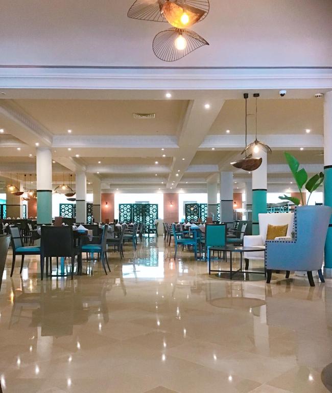 Elegants restorāns ar mūsdienīgu interjeru un plašu telpu, kurā ir stilīgi galdi un krēsli. Gaismas elementi piešķir siltumu un komfortu atmosfērai.