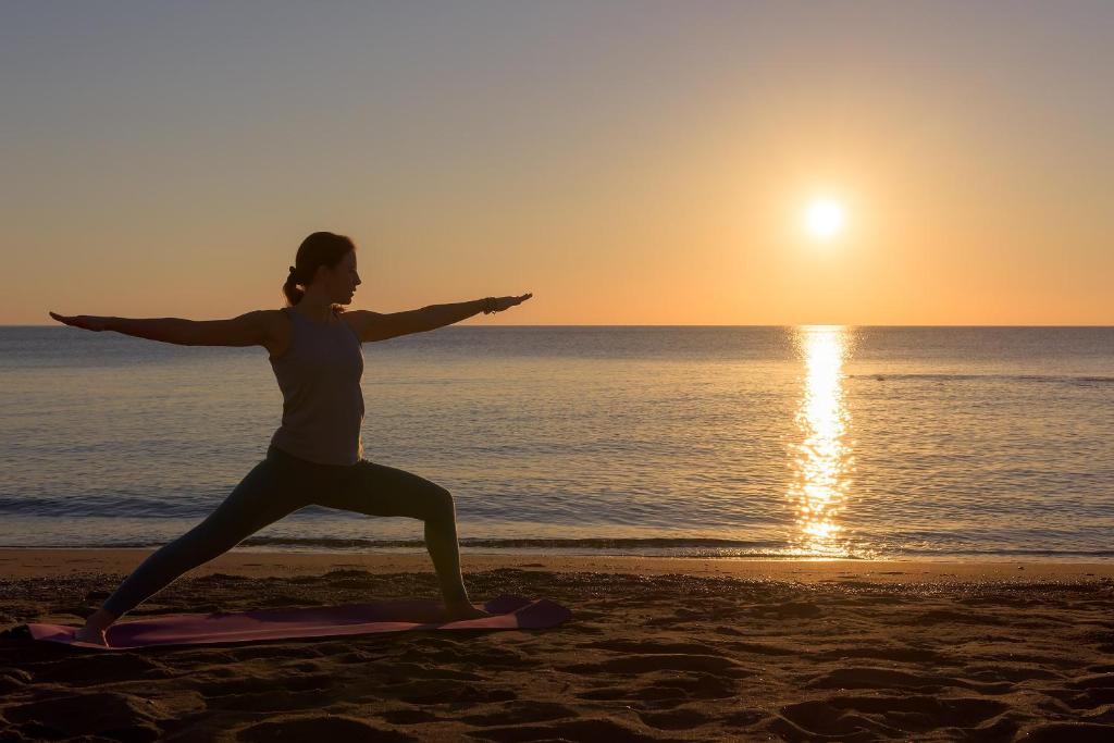 Sieviete veic jogu pludmalē pie Atrium Prestige Thalasso Spa Resort & Villas saulrietā.