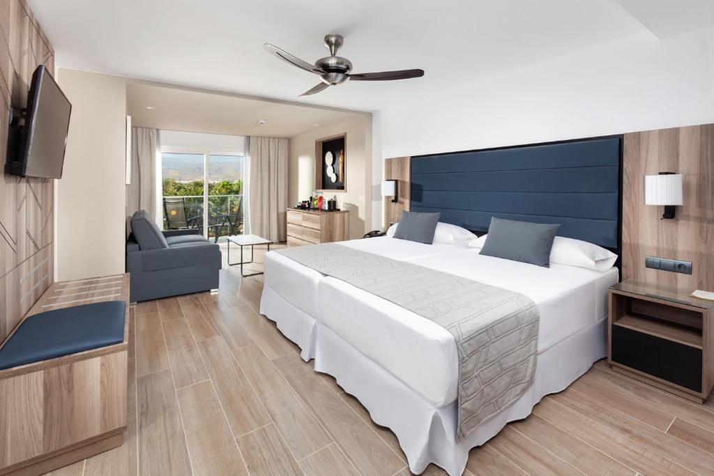 Moderns viesnīcas numurs ar divām gultām, dīvānu un balkonu, kas nodrošina dabisku apgaismojumu. Interjers ir minimālisma stilā ar koka elementiem un komfortu.