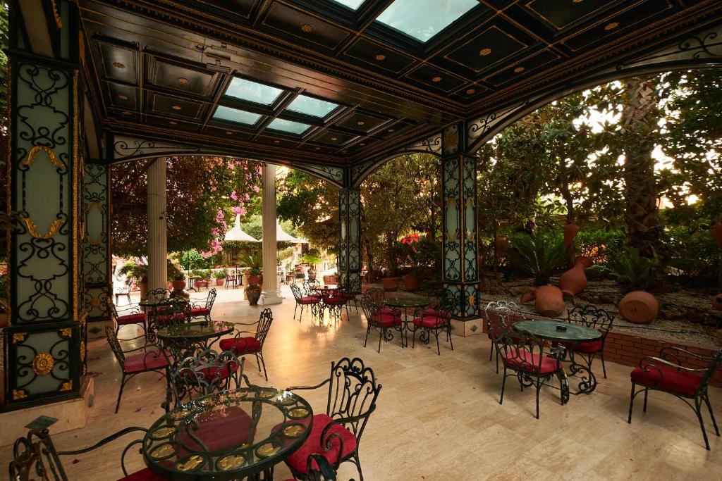 Elegants terases kafejnīca Club Hotel Sera ar dzelzs mēbelēm un zaļumu fonu.