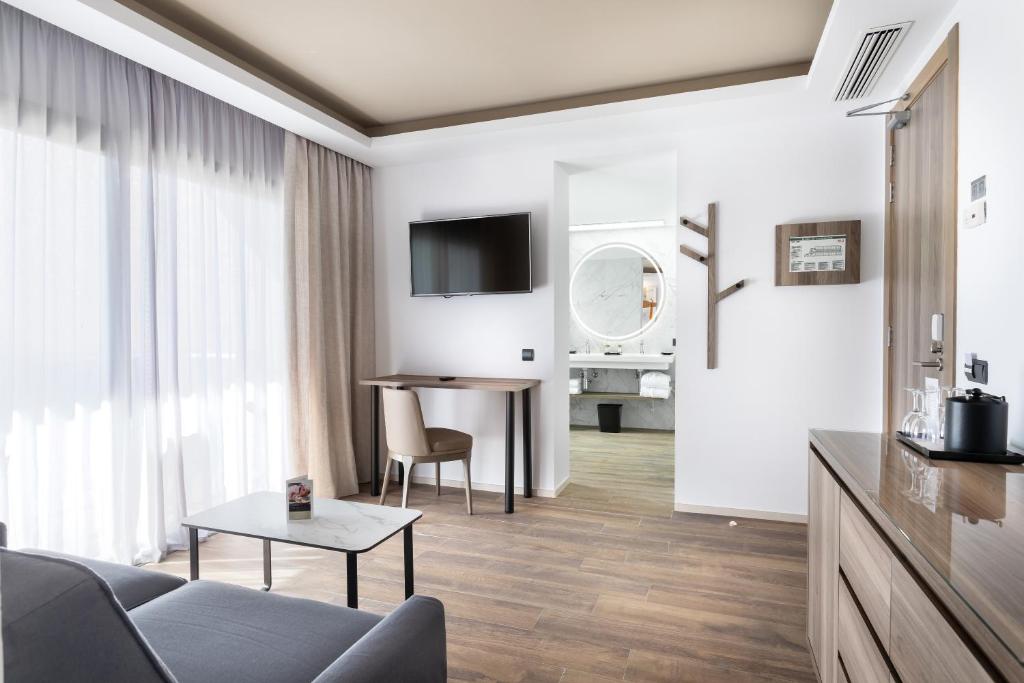 Mūsdienīgs viesnīcas numurs ar ērtu dīvānu, televizoru un darba galdu. Telpa ir gaiša un gaumīgi iekārtota, ar skatu uz vannas istabu.