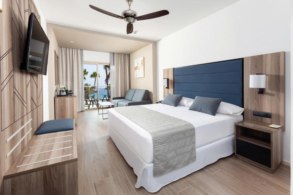 Mūsdienīgs viesnīcas numurs ar divguļamo gultu, dīvānu un balkonu ar skatu uz jūru. Numurā ir televizors, galds un koka apdare, radot patīkamu atmosfēru.