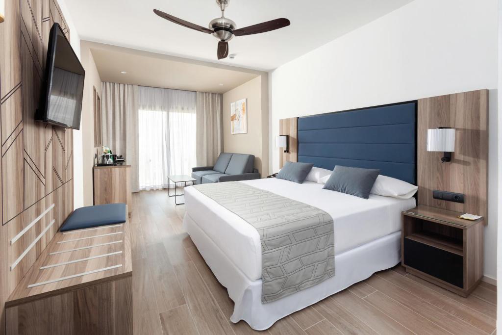 Mūsdienīgs viesnīcas numurs ar divguļamo gultu, dīvānu un televizoru, kas nodrošina komfortu un eleganci. Gaismas un koka akcenti piešķir telpai siltumu.