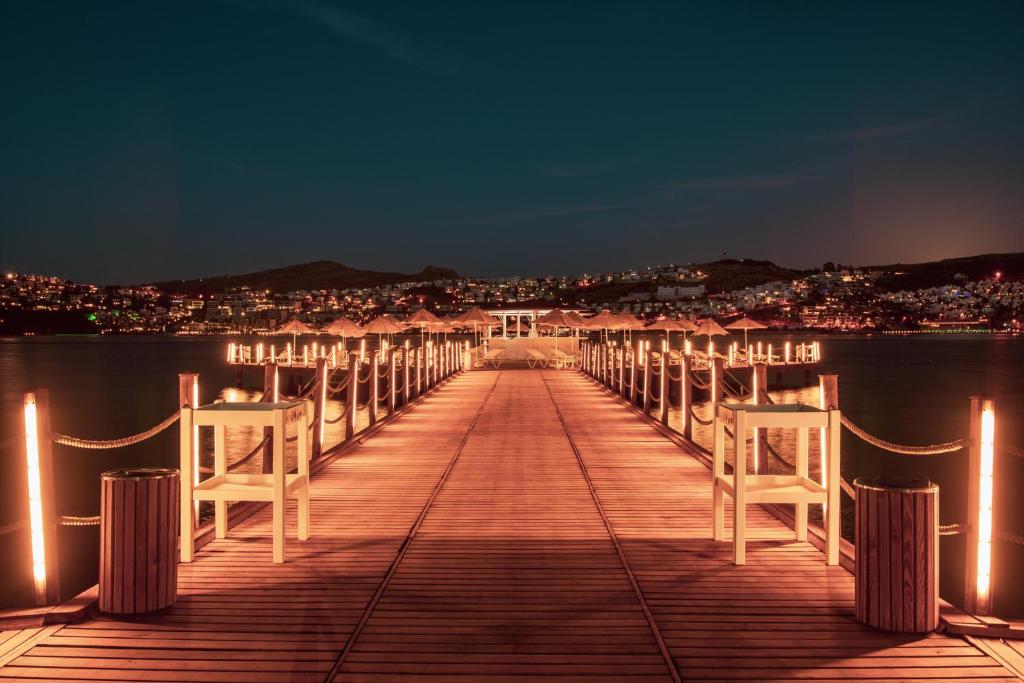 Cenšoties uz koka piestātni pie jūras Hotel Baia Bodrum, apgaismota naktī.