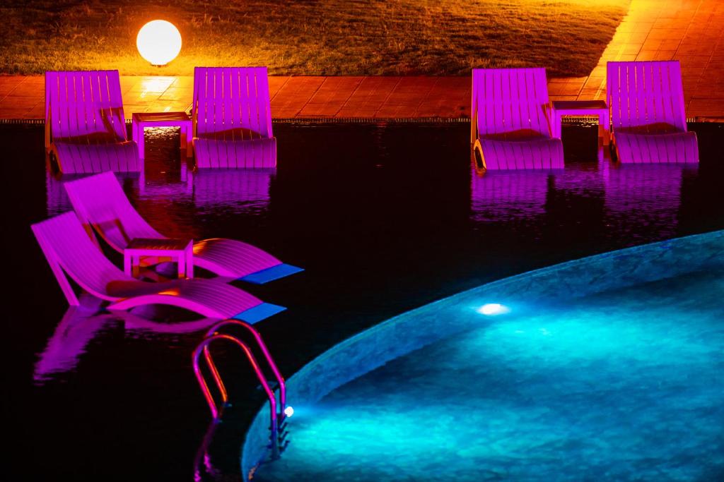 Dizainveida atpūtas krēsli pie baseina Hotel Baia Bodrum, apgaismoti ar krāsainām gaismām.