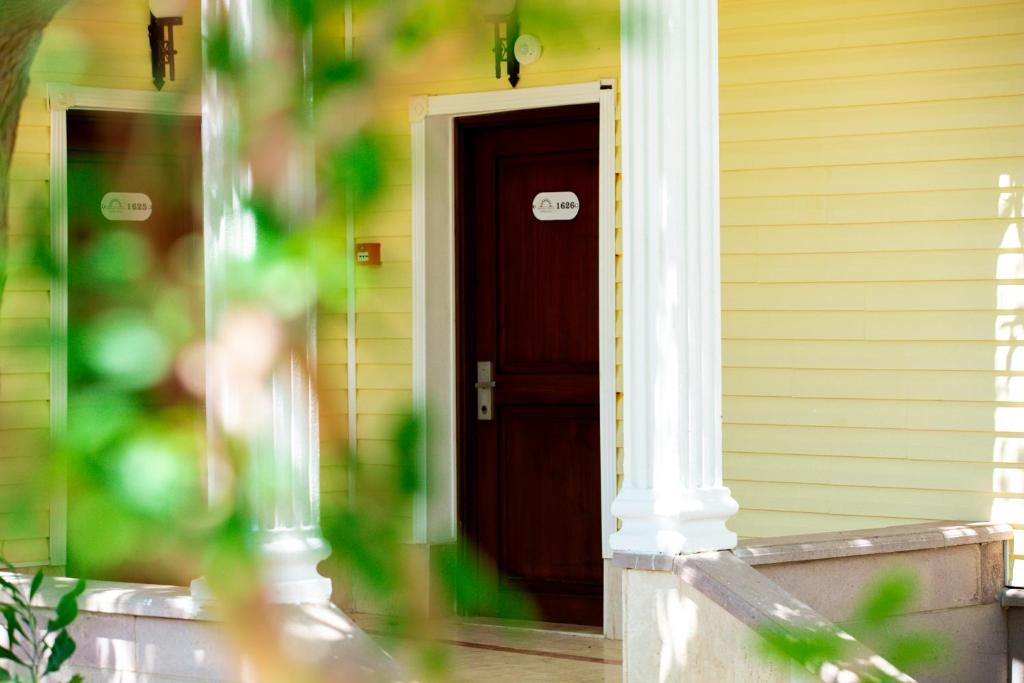 Anadolu Hotels Didim Club numuru ieeja ar dzeltenu fasādi un baltiem stabiem.