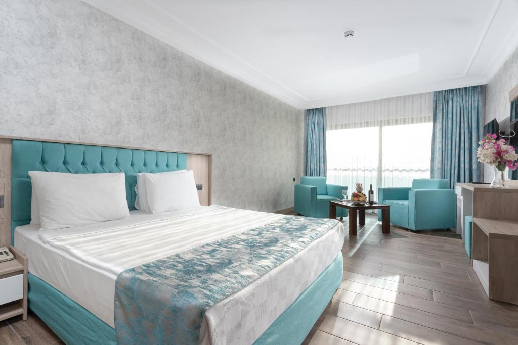 Mūsdienīgs numurs Anadolu Hotels Didim Club ar ērtu gultu un atpūtas zonu.