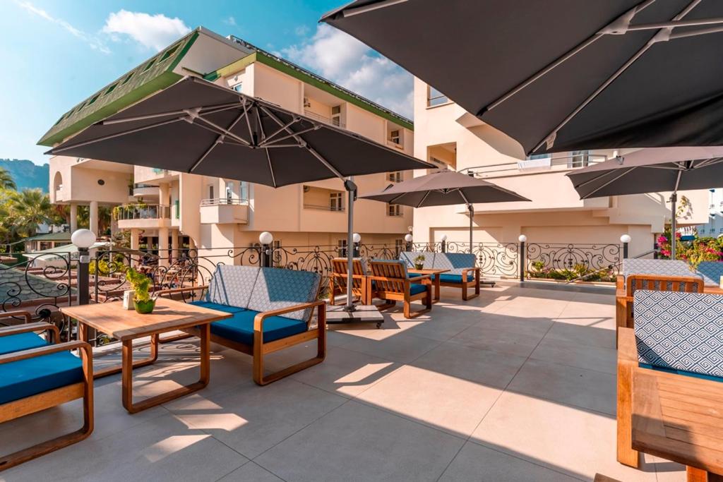 L'ancora Beach Hotel terase ar ērtām mēbelēm un saulessargiem