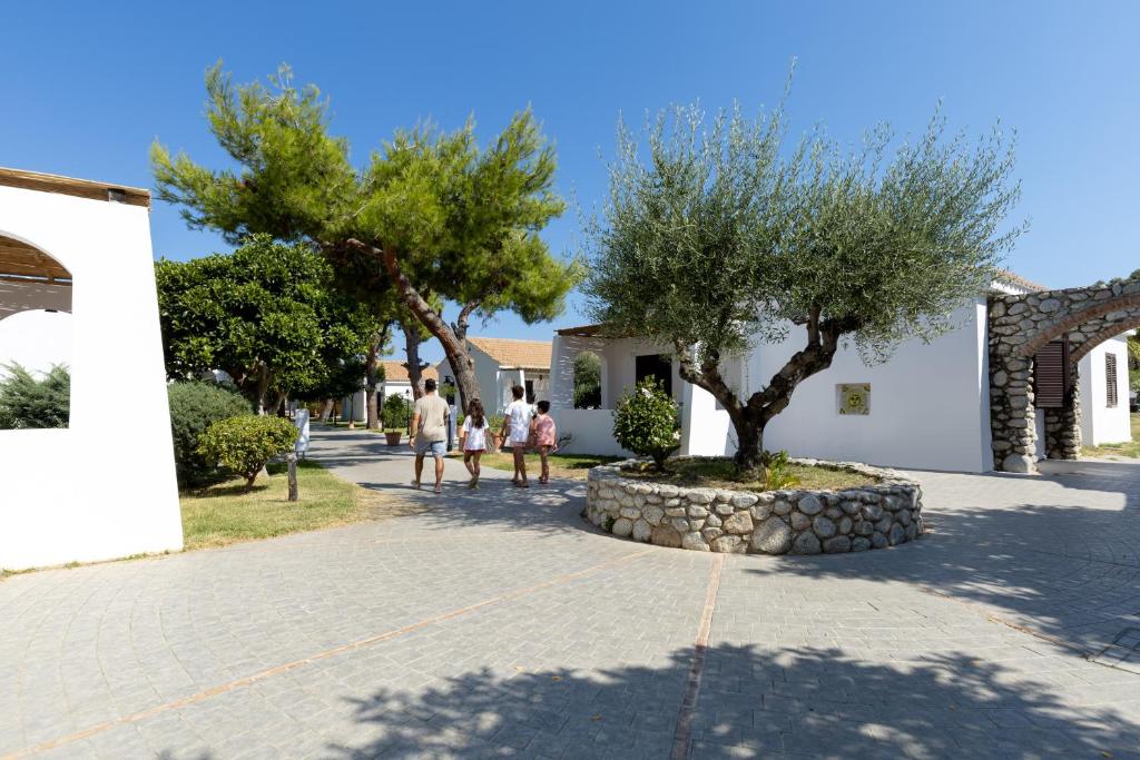 Pastaiga cauri saulainai atpūtas vietai ar zaļām alejām un baltiem namiem, kur ģimene izbauda mierīgu brīvdienu atmosfēru.