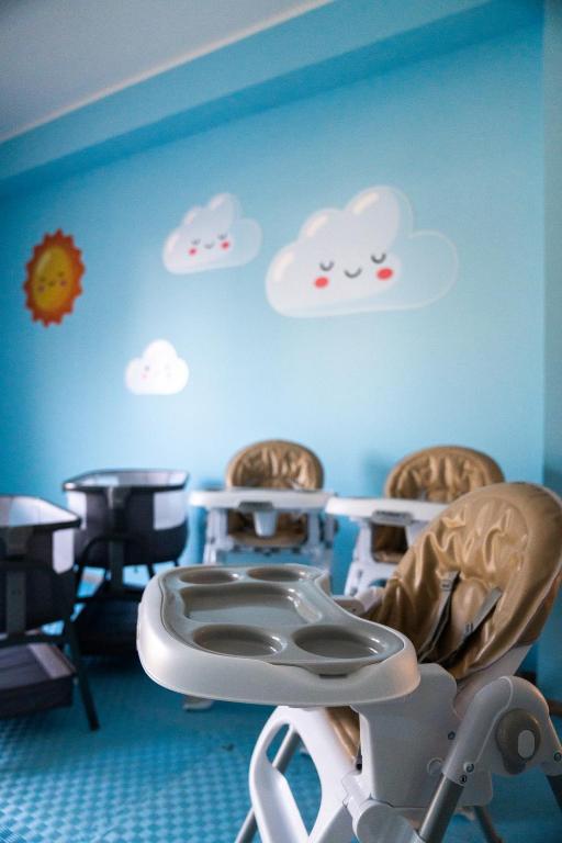 Bērnu barošanas krēsli gaiši krāsotā telpā ar zilo sienu un mīkstiem mākoņiem. Telpa ir draudzīga un piemērota bērniem.