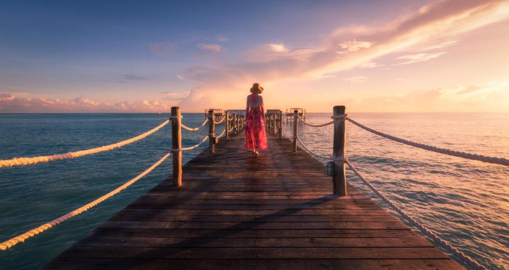 Sieviete uz piestātnes saulrietā Essque Zalu Zanzibar
