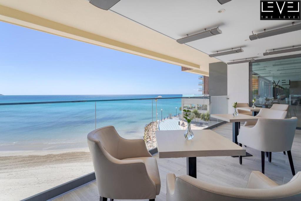 Mūsdienīgs restorāns ar skatu uz jūru, kurā ir gaišas krēslas un galdi. Iekštelpu dizains ir elegants, radot relaksējošu atmosfēru.