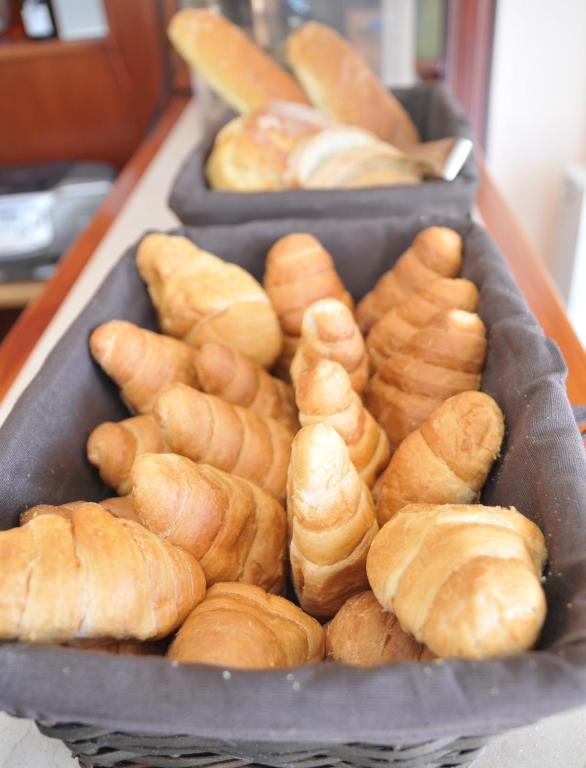 Svaigi cepti kruasāni un maizes rulli, kas pasniegti melnā grozā, radot gardu brokastu atmosfēru.