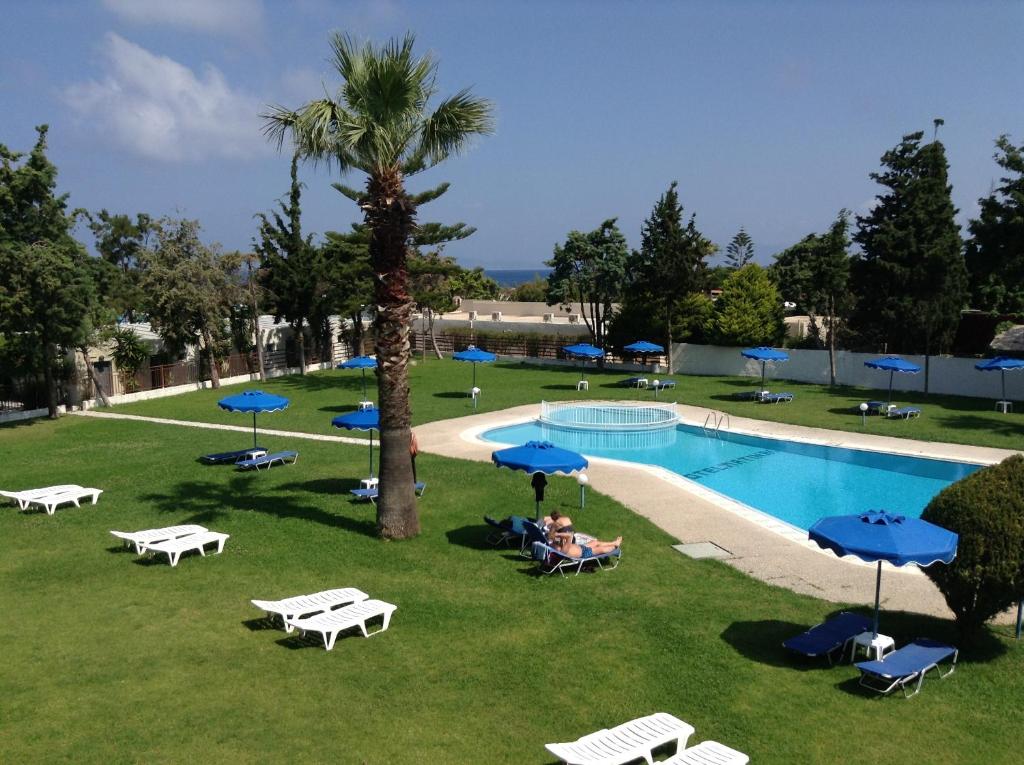 Matoula Beach Hotel peldbaseins ar sauļošanās krēsliem un palmu kokiem
