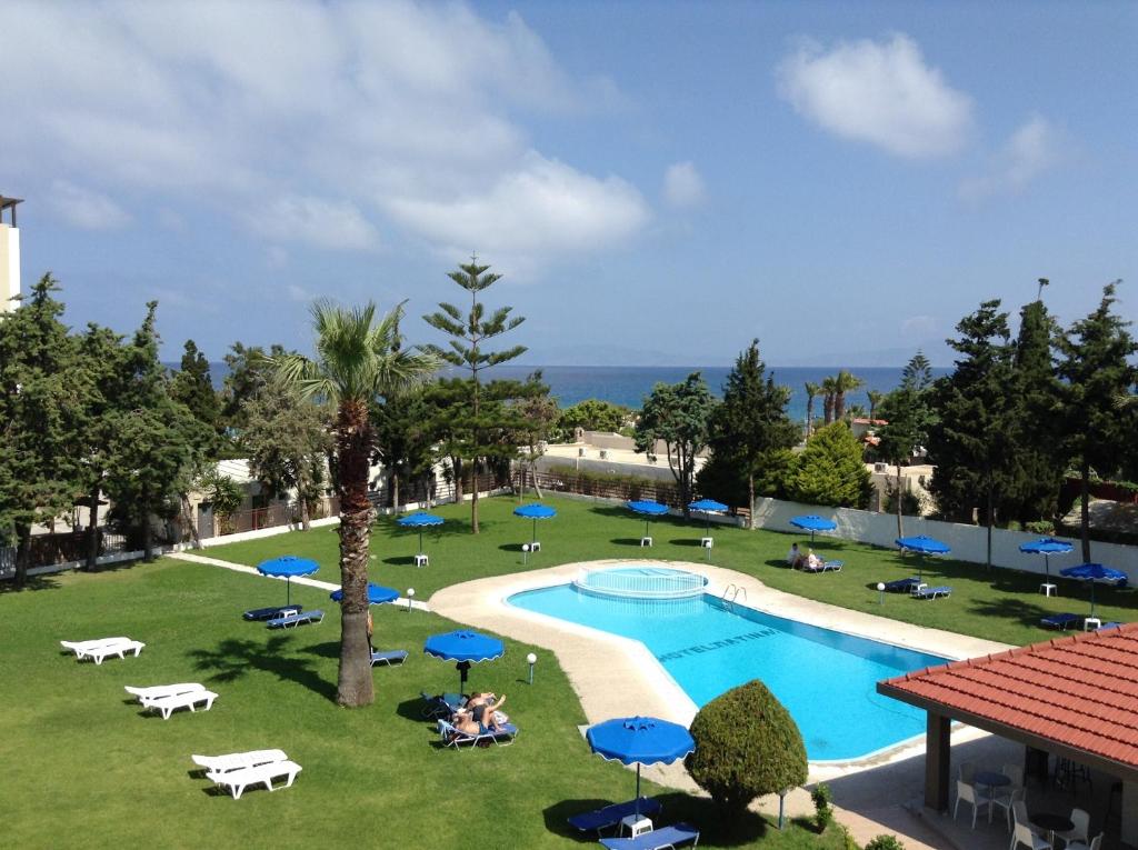 Matoula Beach Hotel baseins ar zilo ūdeni un saulessargiem piekrastē
