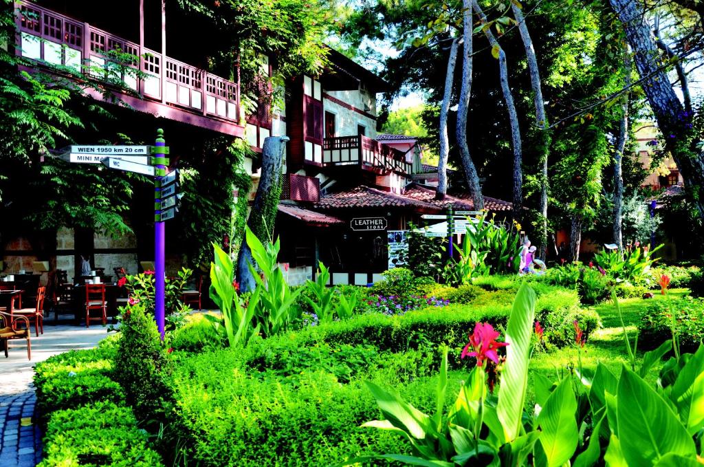 Viesnīcas Ulusoy Kemer Holiday Club dārza ainava ar zaļumiem un ceļvedi.