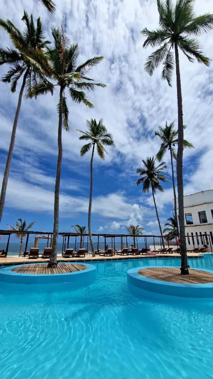 Tropu ainava ar palmām un peldbaseinu, skaidrs debesis un mīksta mākoņu seguma. Ideāla vieta atpūtai un relaksācijai.