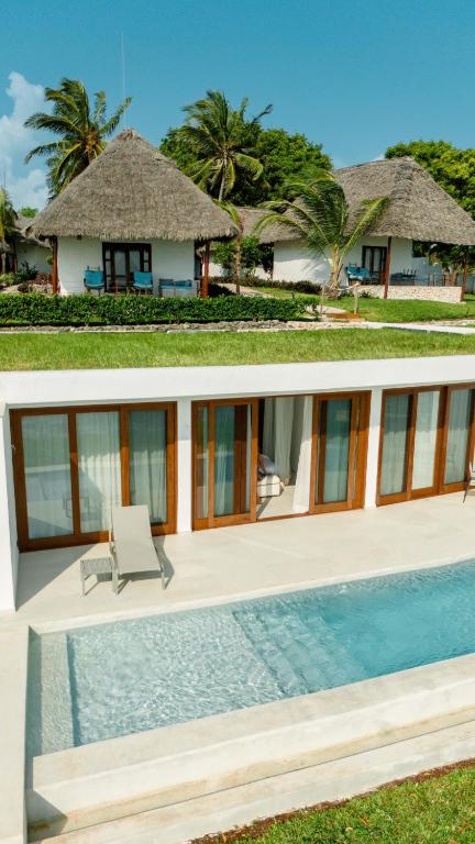 Karafuu Beach Resort & Spa bungalo un baseins tropu vidē.