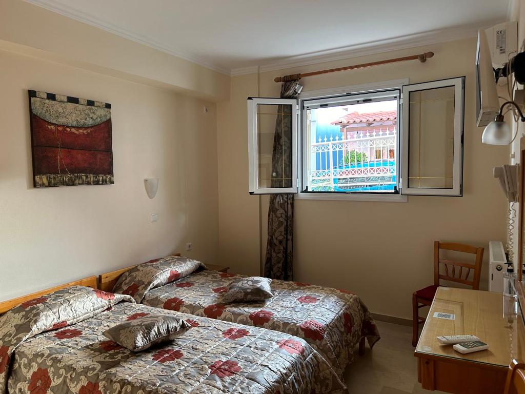 Gaiša viesnīcas numuriņa iekšskats ar divām gultām un logu, kas skatās uz ārpusi. Telpā ir koka galds un krēsls, kā arī mākslas darbs uz sienas.