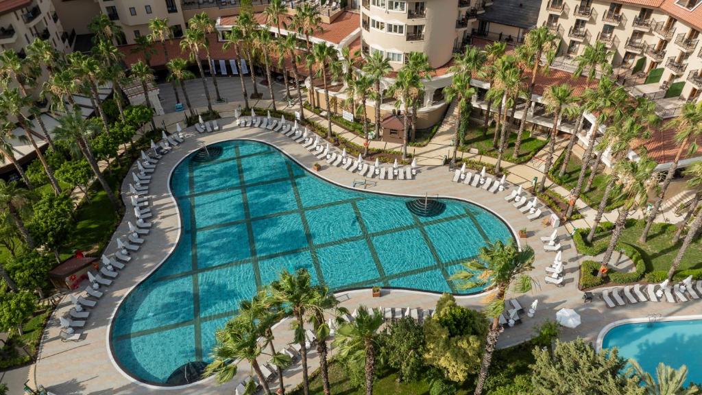 Numa Club Side viesnīcas peldbaseins ar palmām un sauļošanās krēsliem