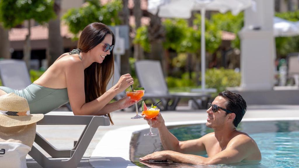 Pāris atpūšas pie baseina ar kokteiļiem Numa Club Side