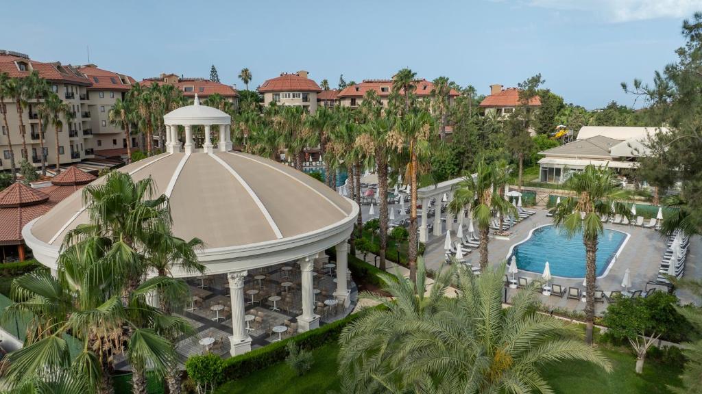 Skats uz Numa Club Side viesnīcas baseinu un terasi, apkārt palmām.